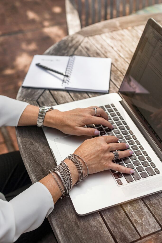 A woman sitting at a table and typing on a laptop.