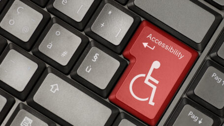 Part of a computer keyboard, but the enter key is red with the accessibility symbol on it.