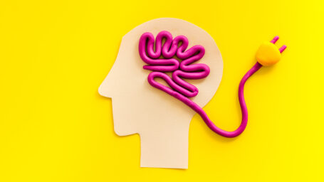creative graphic: shape of a head on a yellow background with a pink cord wound inside in the shape of a brain, with plug extended out