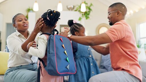 Parent helping their two children get ready for school