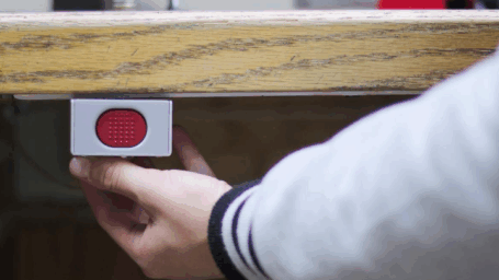 Person holding emergency alarm under desk