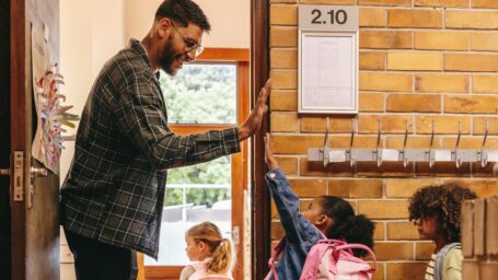 Teacher high fives student as she enters the classroom