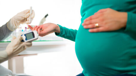 A close-up of a pregnant woman having her blood sugar/ glucose checked.