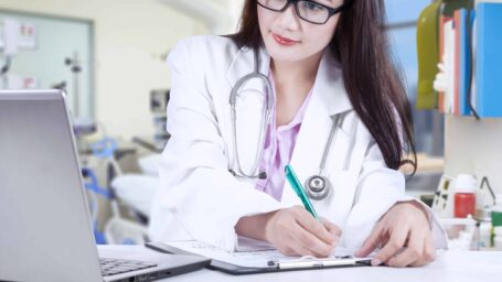 Attractive female doctor is writing medical report at the clinic