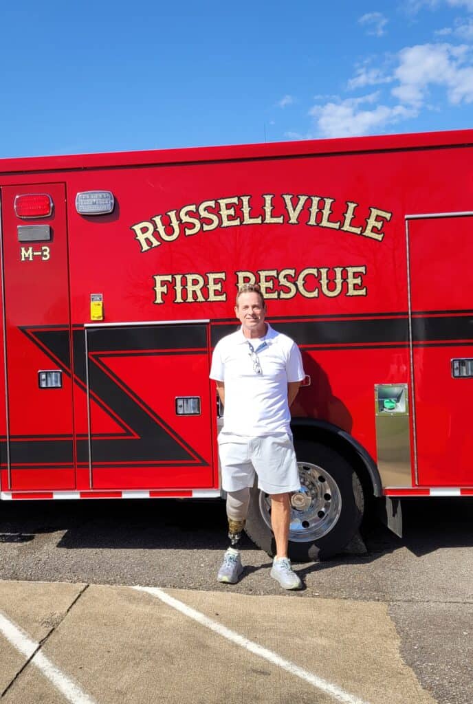 Picture of stroke survivor Robert Caldwell standing in front of an ambulance
