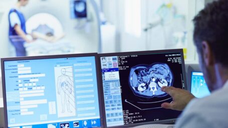Male doctor running CT scan from control room at hospital
